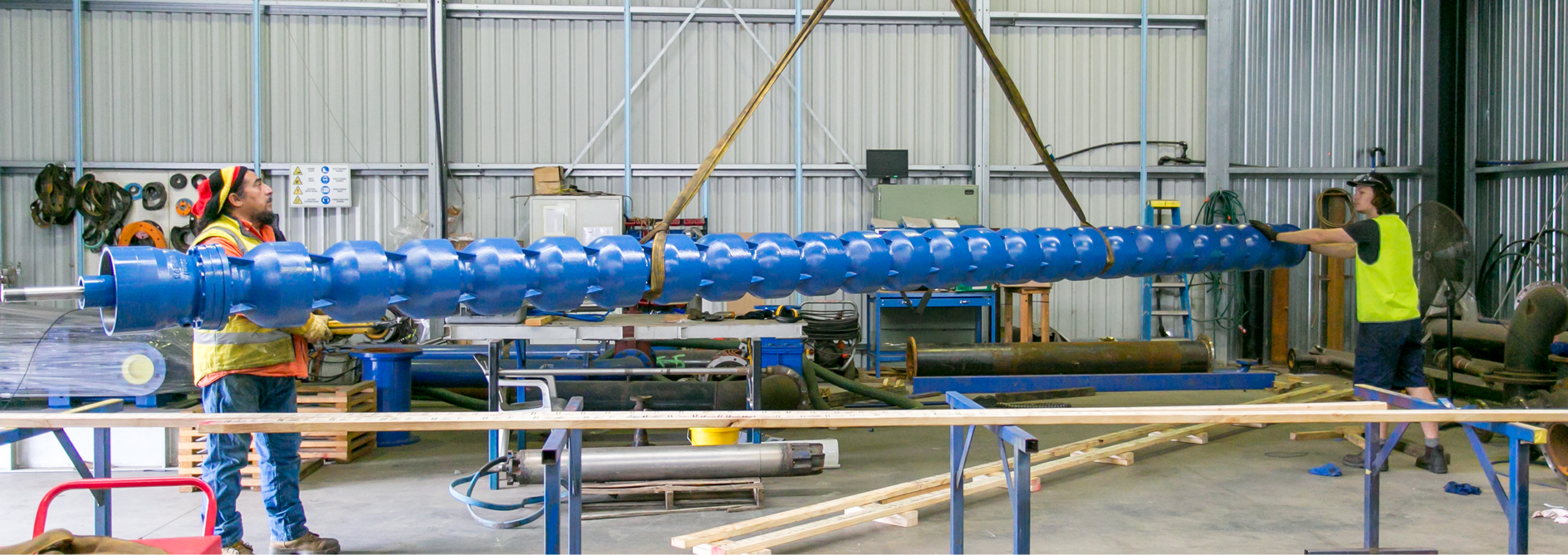 Blue screw conveyor being installed by workers